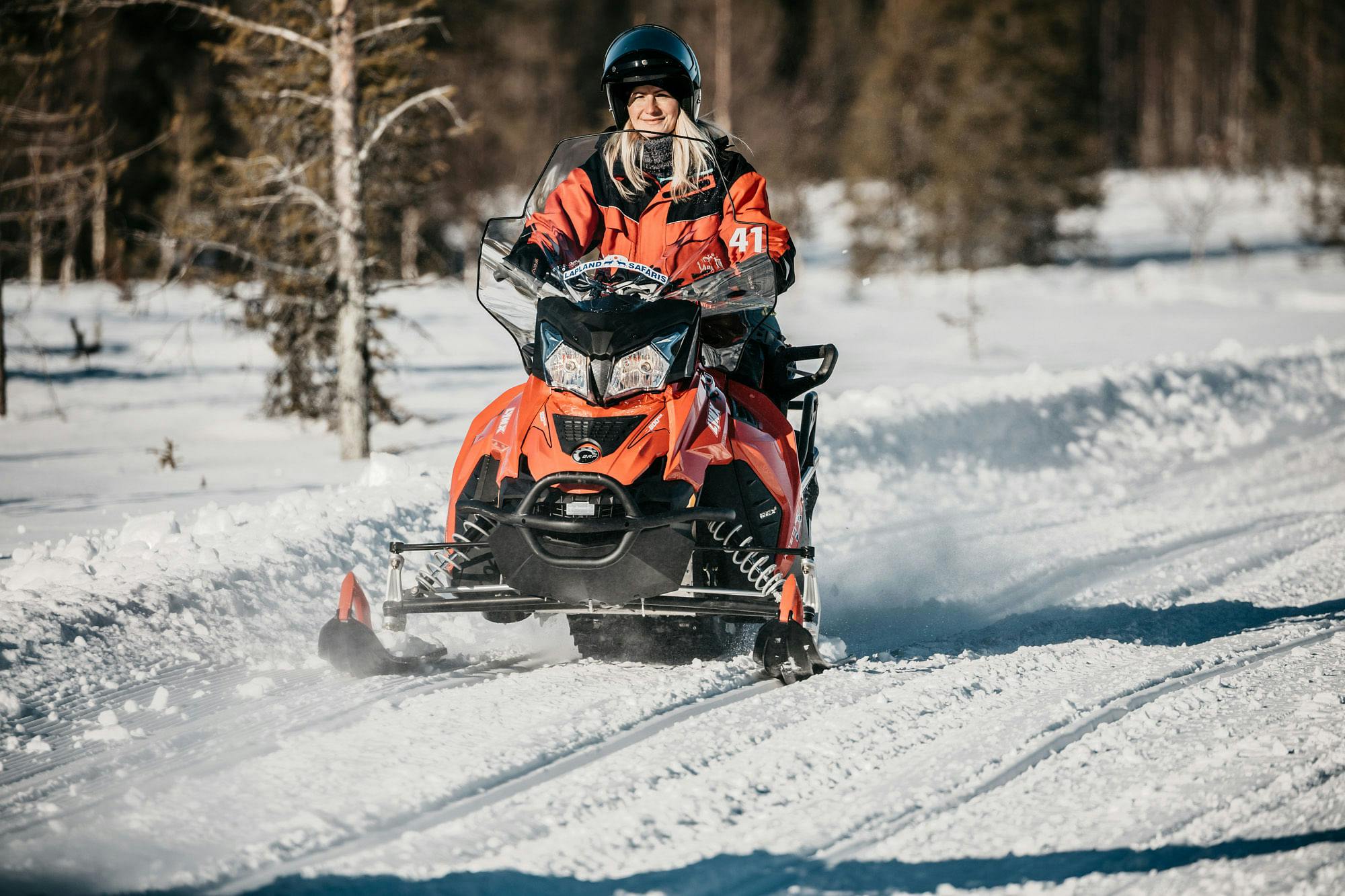 Nainen moottorikelkkailemassa Ylläksen lumisissa maisemissa.