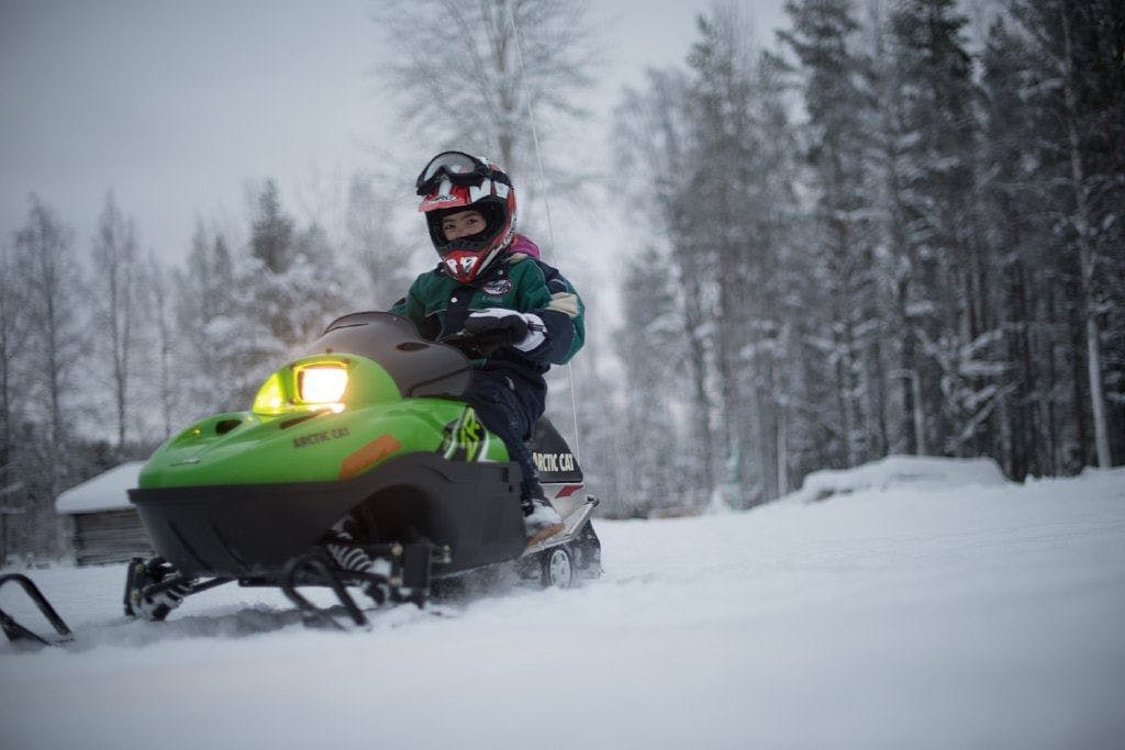 Lapsi testailemassa moottorikelkkaa safarilla, joka tarkoitettu perheille Levillä.