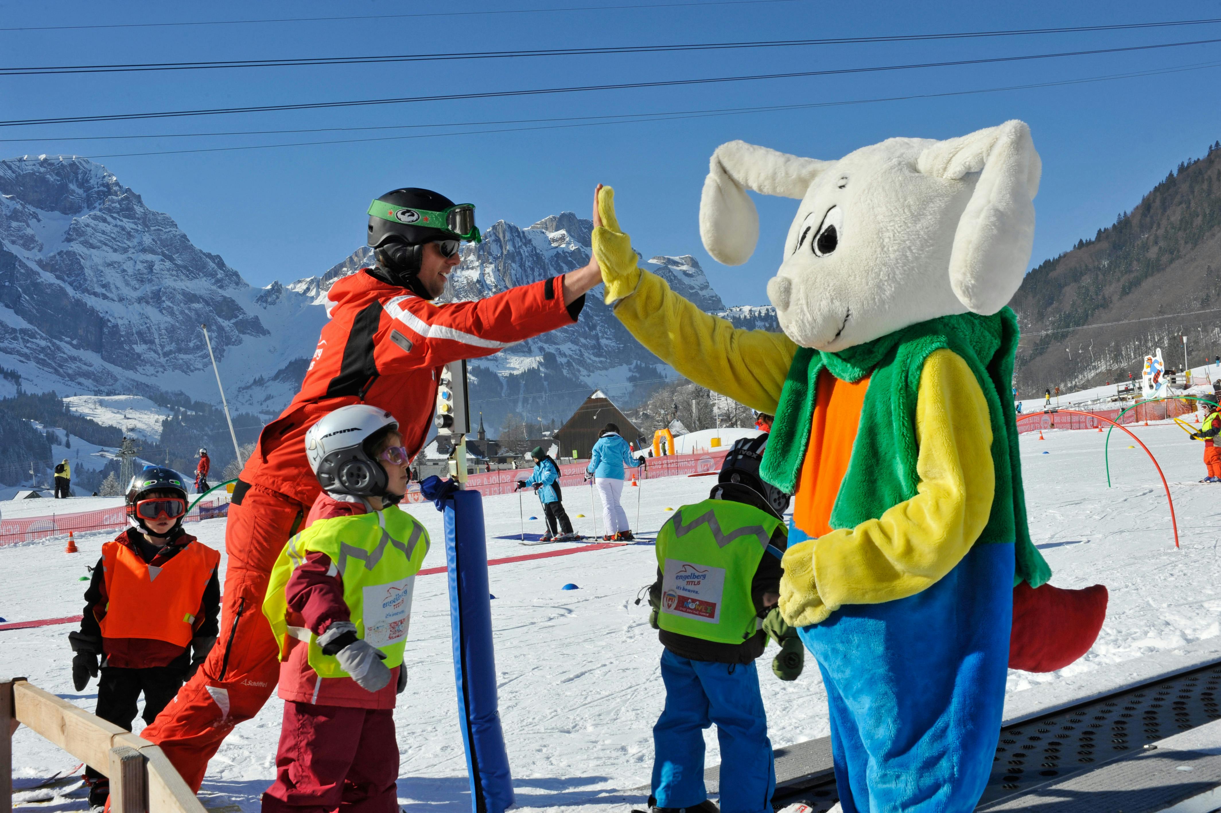 Engelbergin hiihtokoululaiset antamassa ylävitosia maskotille.