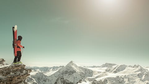 Laskettelija Engelbergin vuoristossa tähyilemässä maisemia sukset selässä.