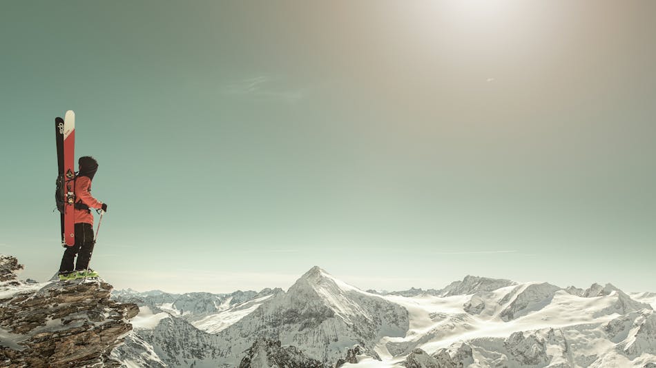 Laskettelija Engelbergin vuoristossa tähyilemässä maisemia sukset selässä.