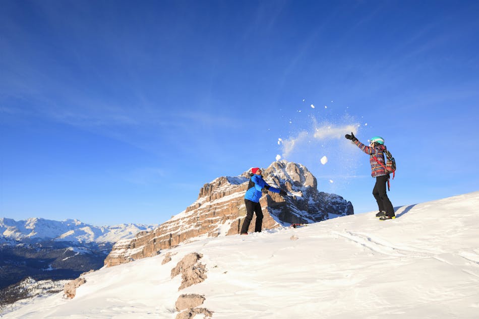 Kaksi henkilöä heittävät lunta ilmaan Madonna di Campiglion rinteissä.