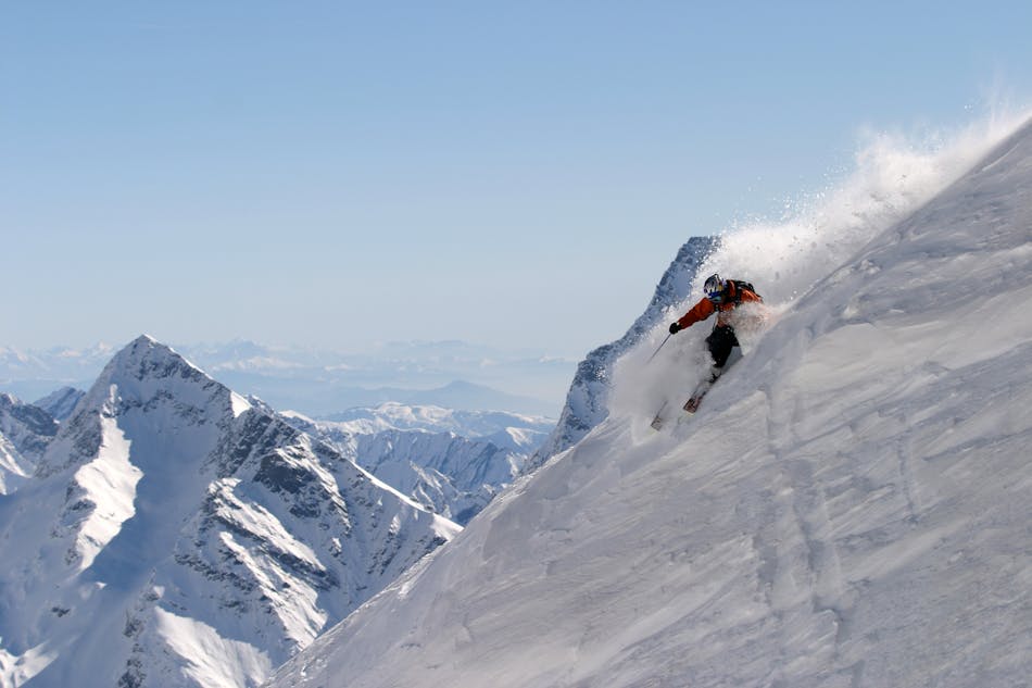 Jyrkässä Monte Rosan offari-rinteessä laskettelija tekemässä käännöstä, jossa lumi pöllyää.