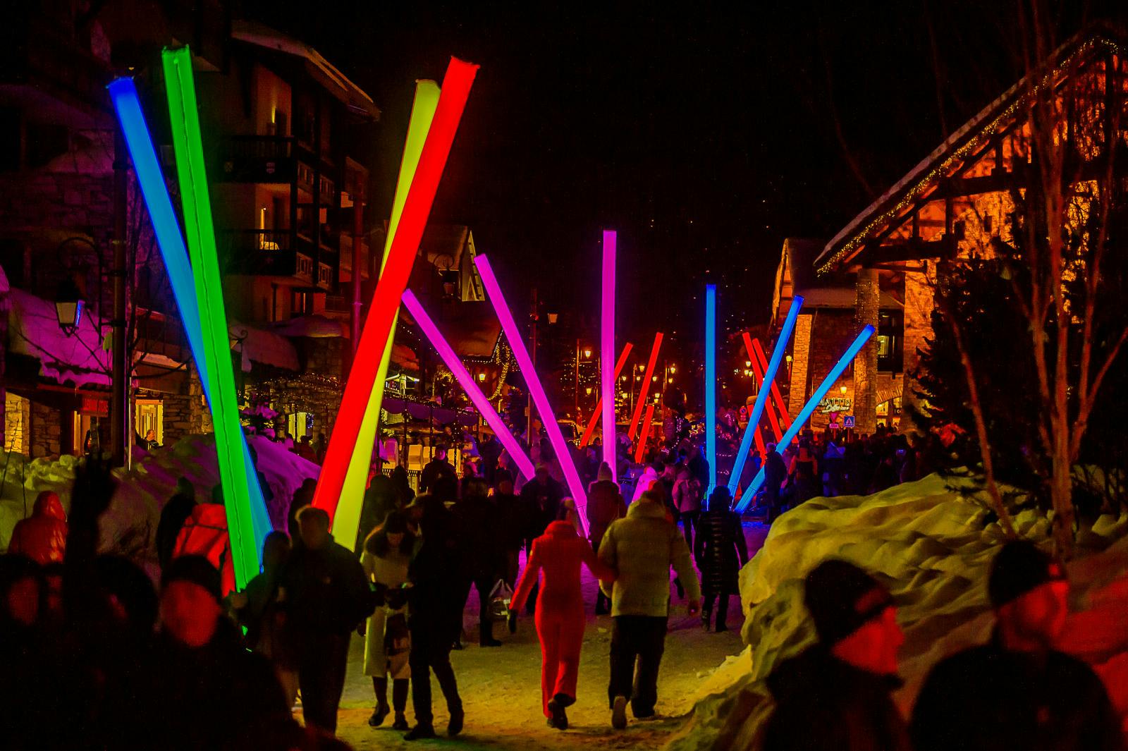 Valotapahtuma Val D’isèressä. Kaupunki täynnä eri värisiä valotikkuja ja ihmiset kävelevät niiden ympäröimänä.