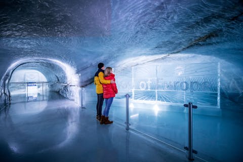 Pariskunta tutkimassa Jungfraujochin jääpalatsia sisältä. Top of Europe jääveistosta katsovat.
