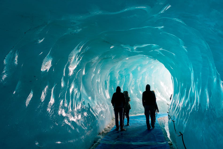 Mer de Glace jääluola Chamonixissa. Neljä ihmistä kävelee jääluolaa pitkin.