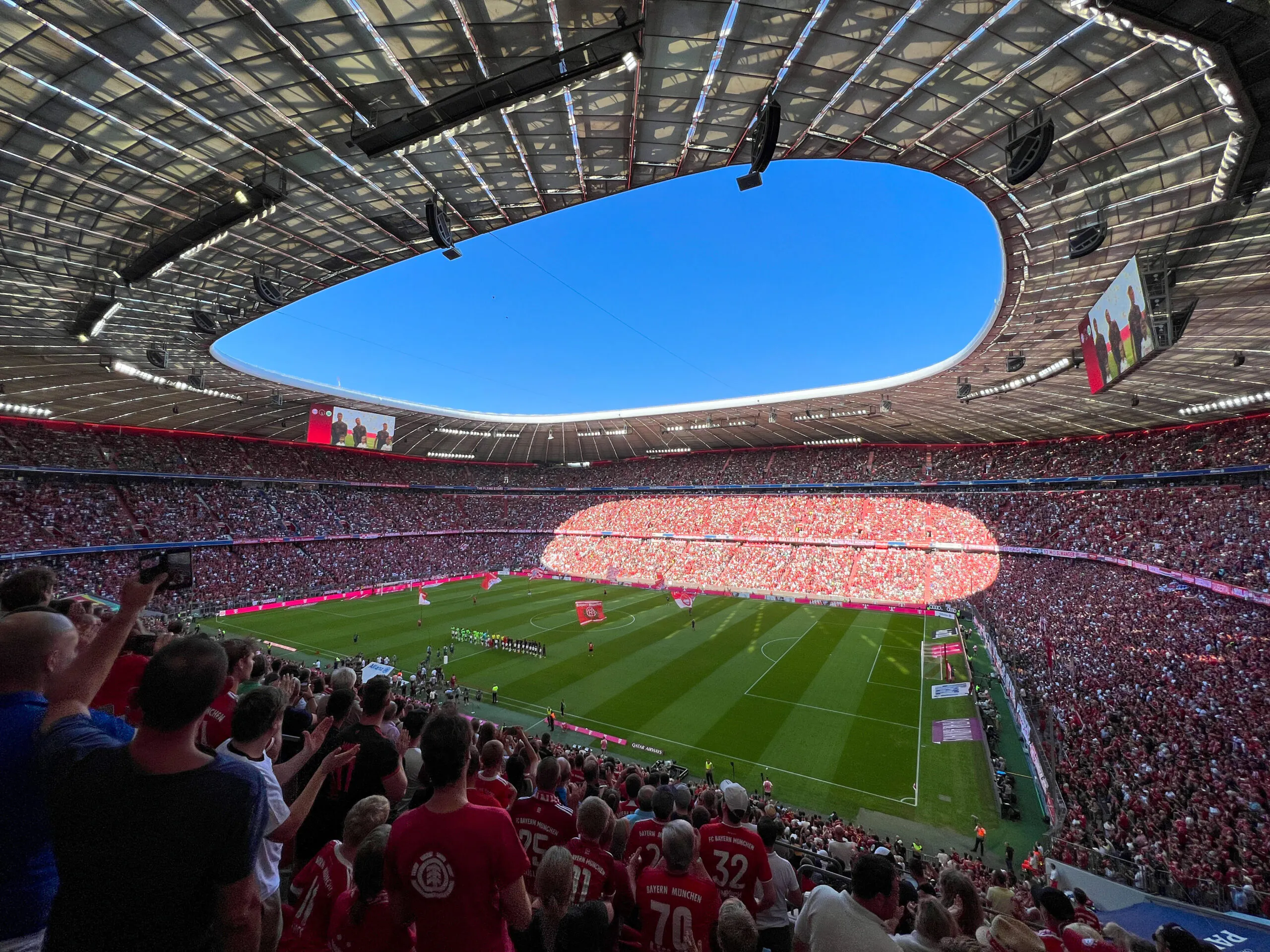 Allianz Arena, Munchen, Saksa. Jalkapallostadionilla peli käynnissä ja katsomossa fanit kannustamassa.
