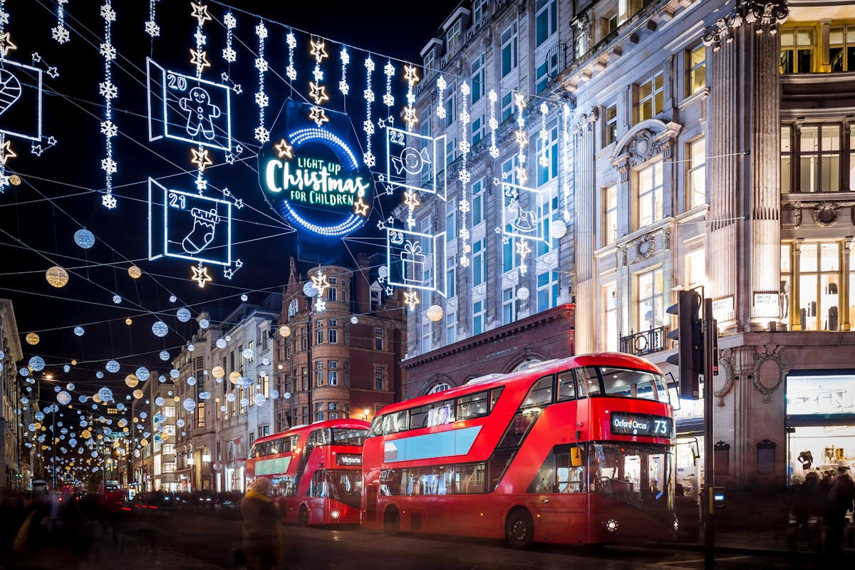 Katukuva Lontoon jouluvaloista ja punaisesta kaksikerroksisesta bussista illalla.