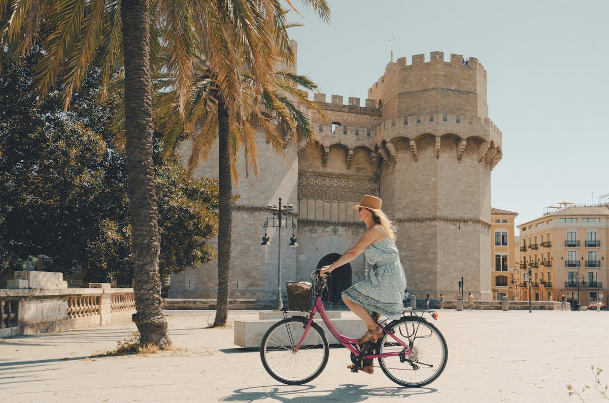 Nainen ajaa polkupyörällä Torres de Serranosin kaupungin portilla Valenciassa Espanjassa