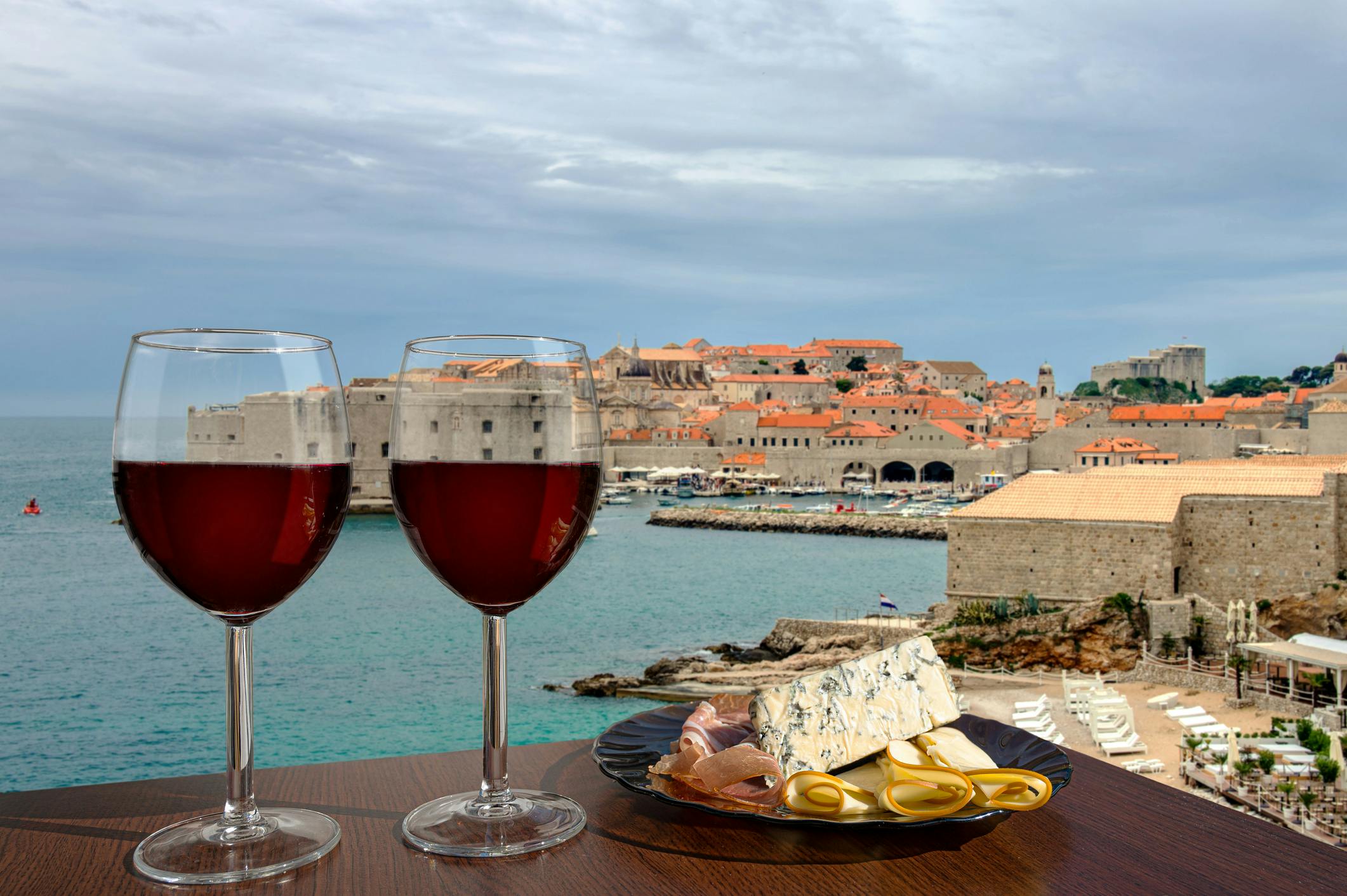 Lasilliset punaviiniä Dubrovnikin keskustaa vasten ja ruokalautanen.