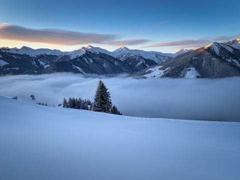 Luonnonkaunis näkymä lumen peittämille vuorille ja pilvien peitto hiihtokeskuksessa Saalbach Hinterglemm.