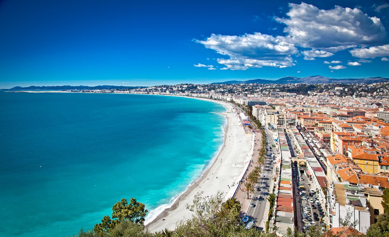 Ilmanäkymä Nizzan rantamaisemasta. Valkoinen pitkä hiekkaranta, turkoosi meri sekä kaupunkimaisemaa
