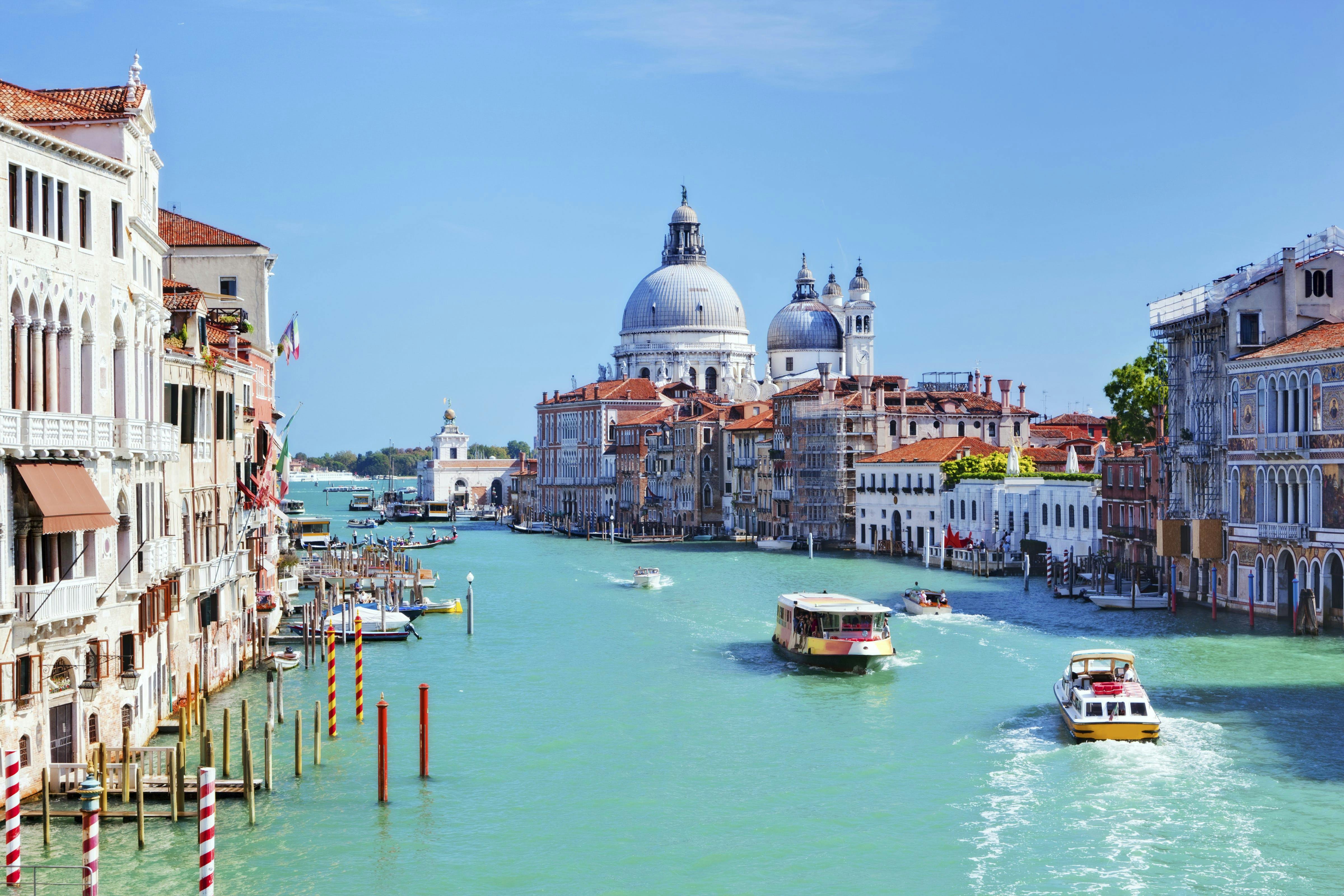 Näkymässäkanava, jossa useita Venetsialaisia veneitä sekä taustalla Santa Maria della Salute kirkko