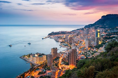 Monacon Monte Carlo ilmanäkymä illalla, tiet valaistuna ja taivas vaaleanpunaisena