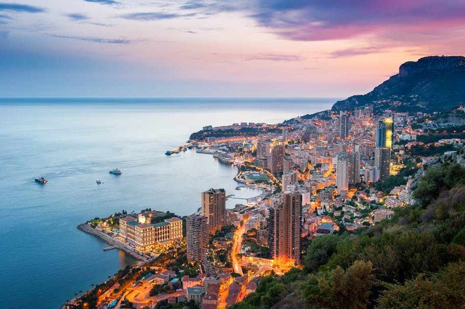 Monacon Monte Carlo ilmanäkymä illalla, tiet valaistuna ja taivas vaaleanpunaisena